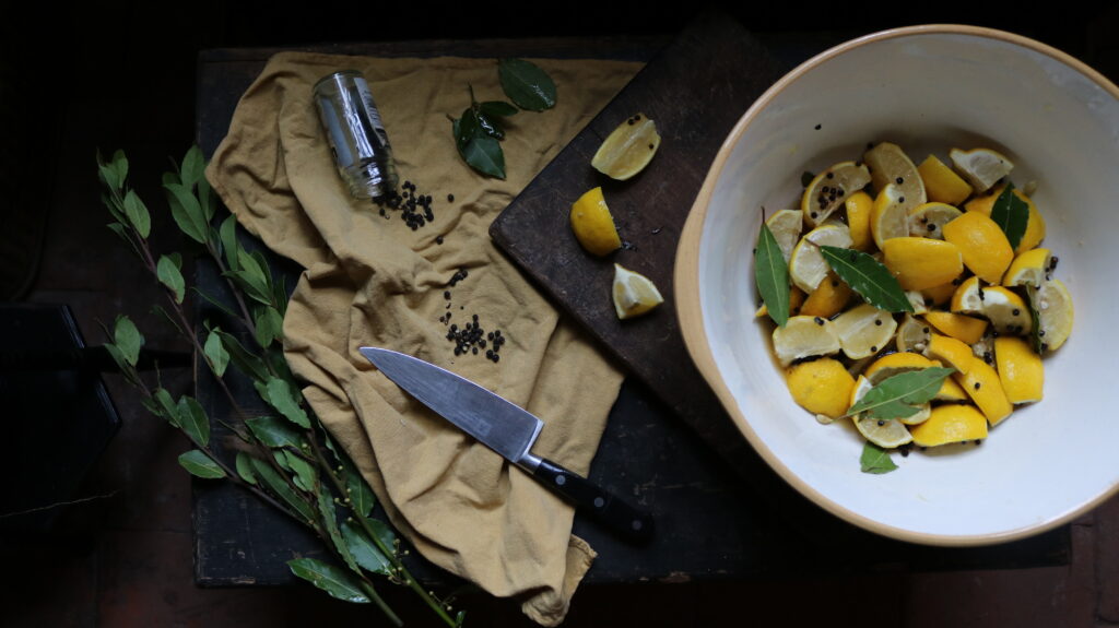 Adding bay leaves and peppercorns to the lemons